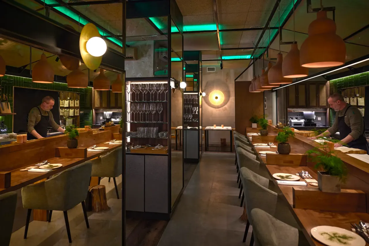 The dining room at El Invernadero seen lengthways, with the copper lamps lit above the tables