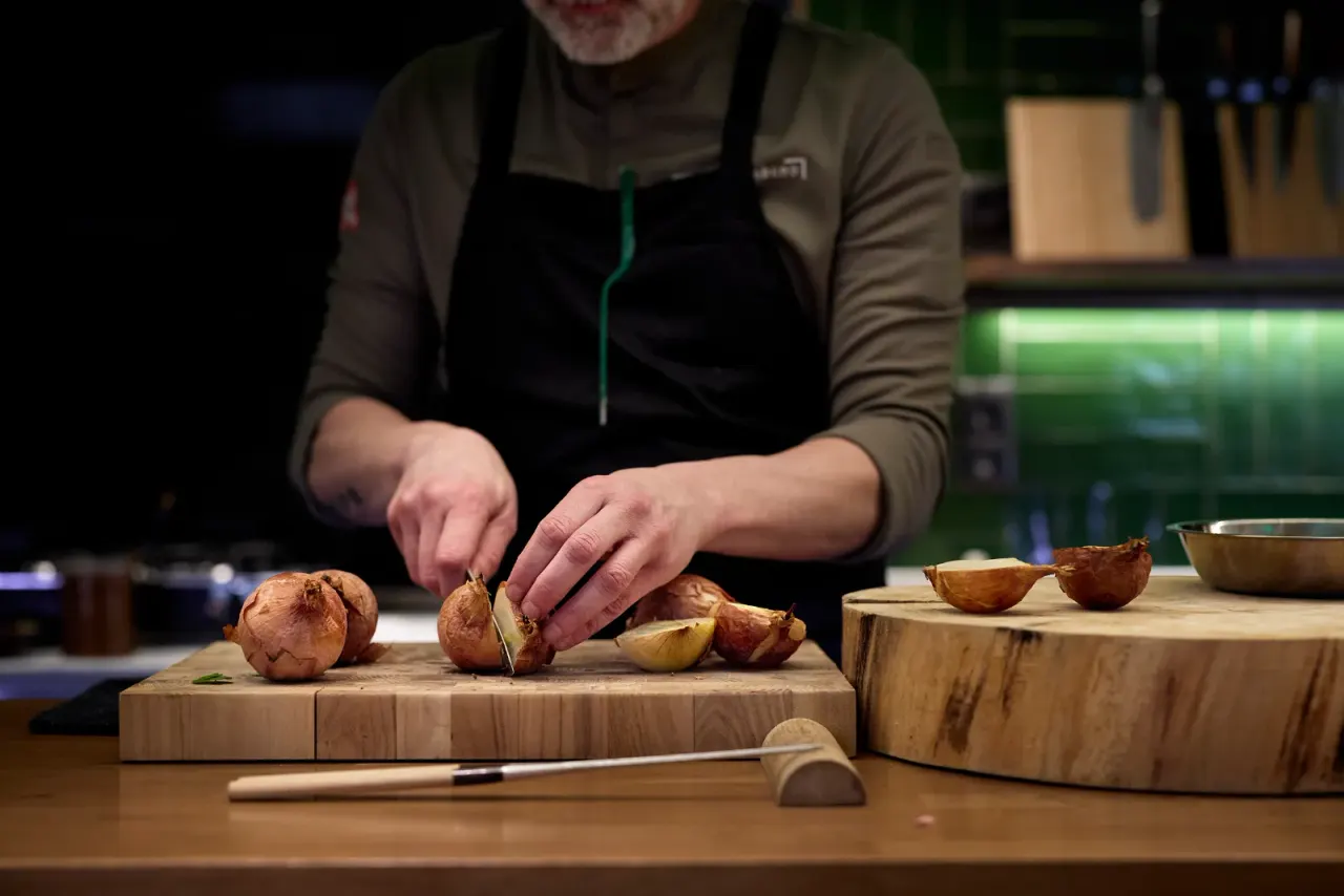 Rodrigo de la Calle cutting roasted onions on the wooden board in the kitchen