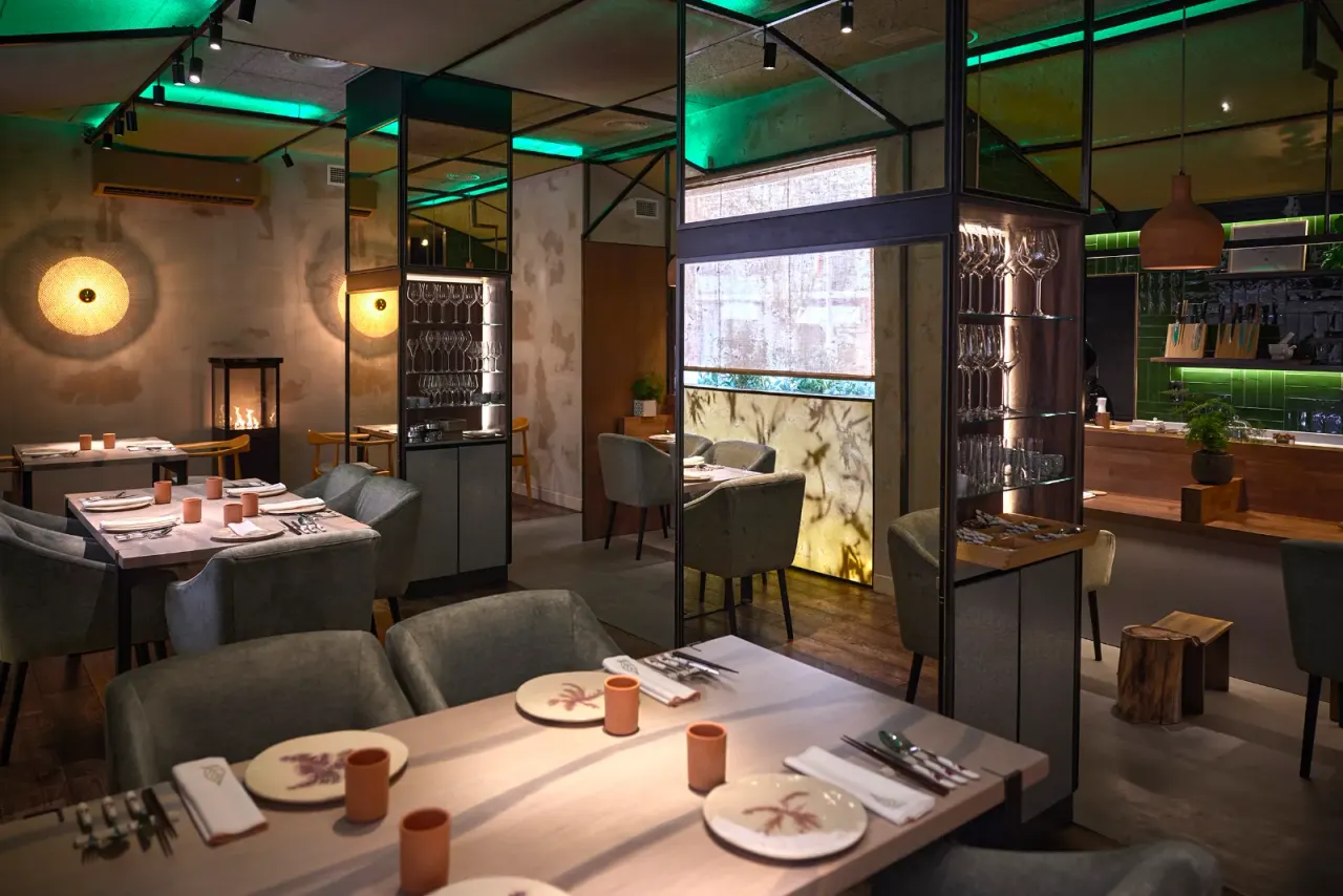 A laid table in the dining room at El Invernadero with the green light of the room behind