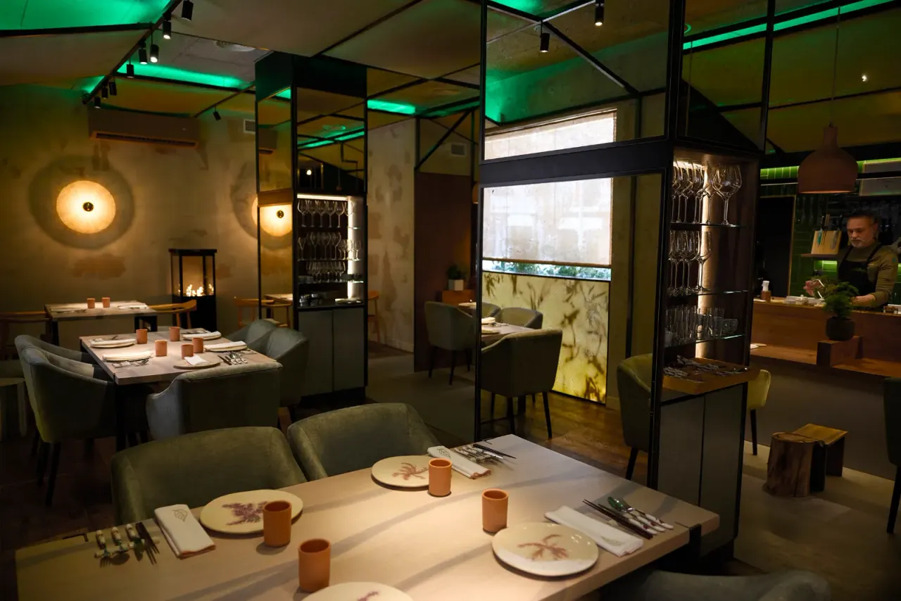 The dining room at El Invernadero with the tables laid and the plant-filled window behind