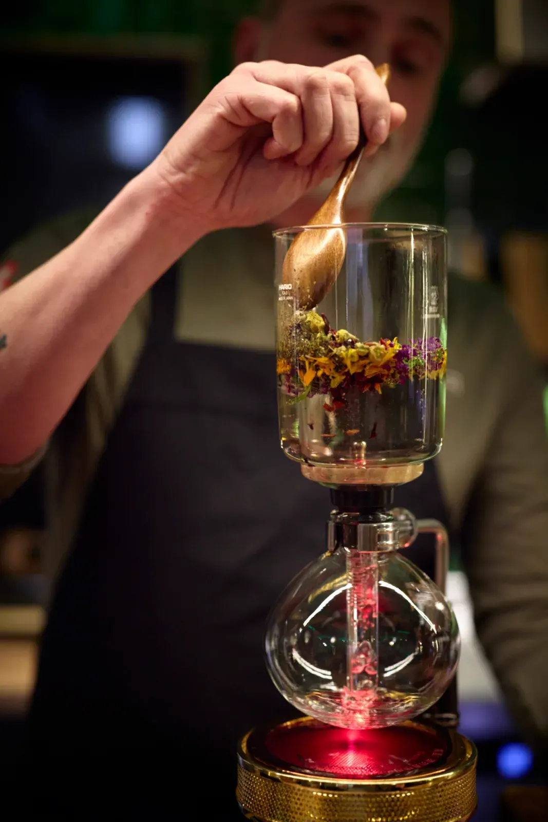 Dried flowers and herbs in the glass chamber of the siphon, stirred with a wooden spoon before extraction