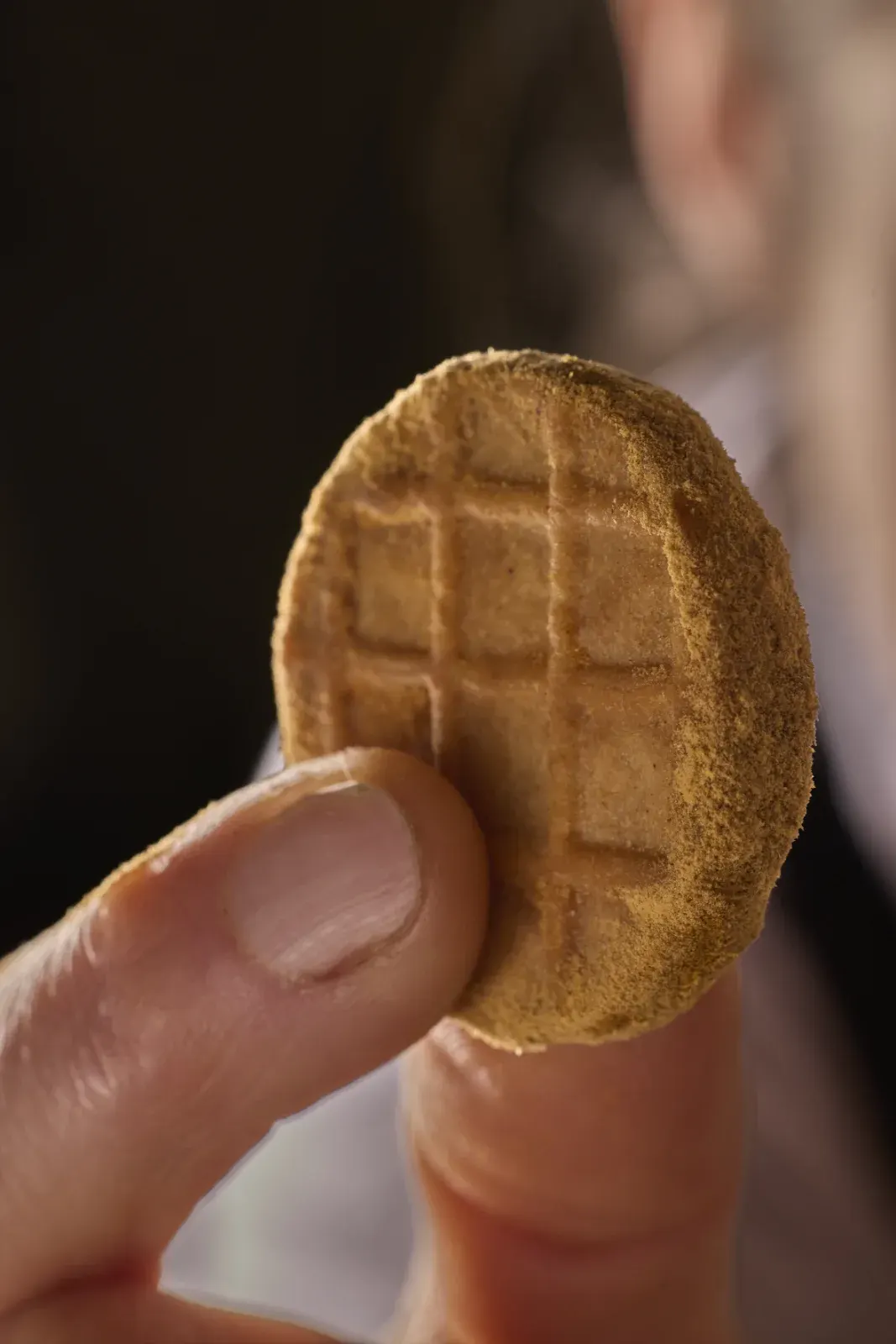 A thin waffle held between the fingers, one of the house's sweet bites