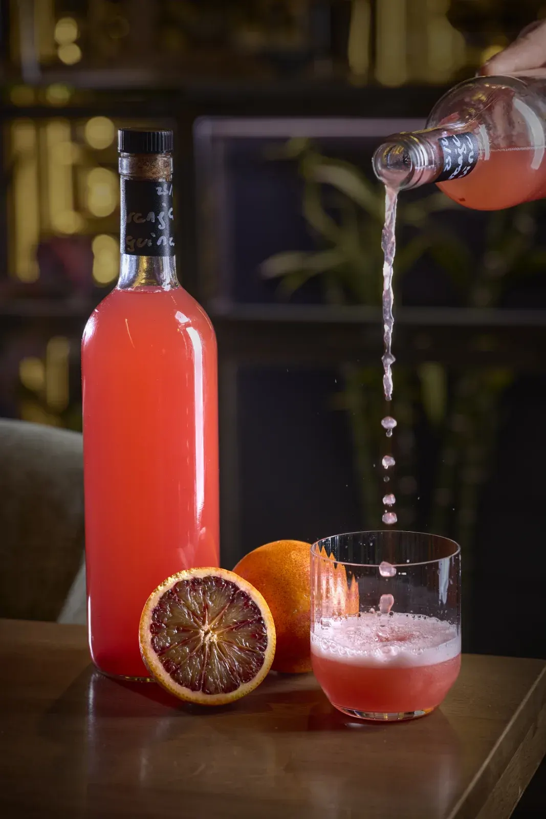 A blood orange drink being poured beside the cut fruit