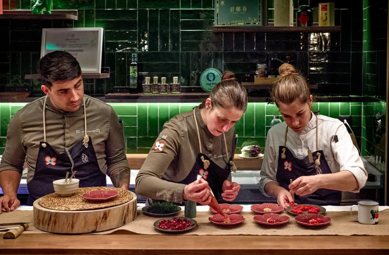 Three cooks plating at the same time in the open kitchen at El Invernadero
