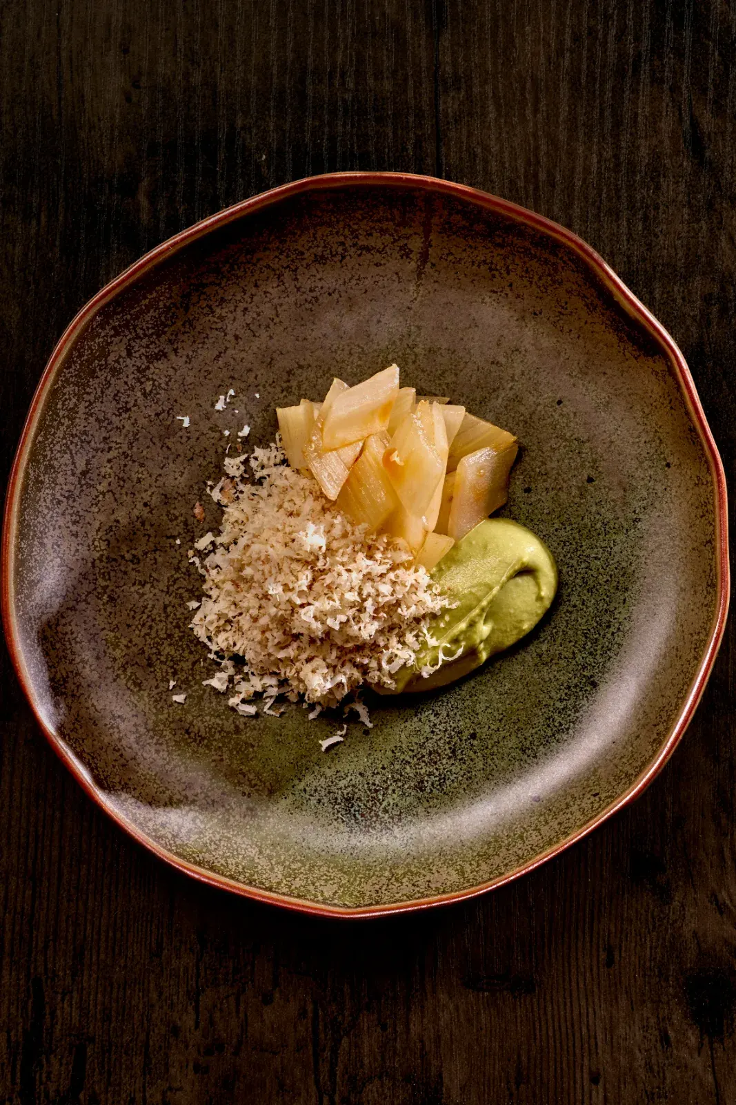 Celery with tea and walnut: green cream, slices and crumble on a ceramic plate