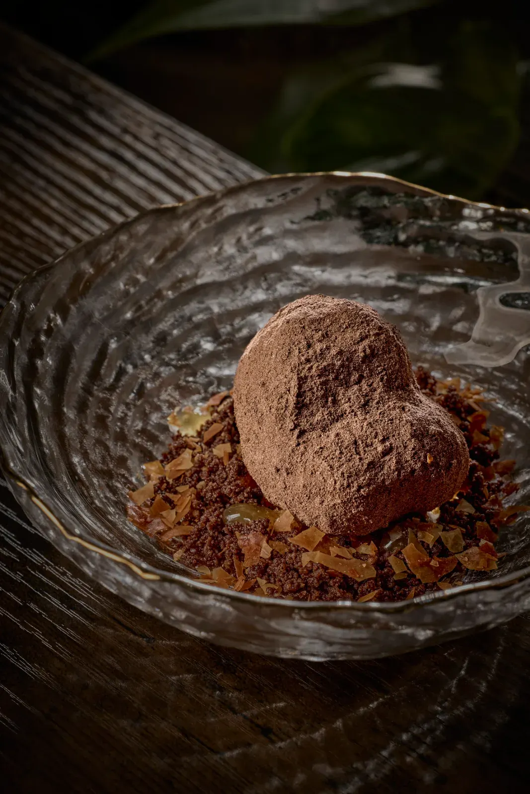 A bite dusted with cocoa over its crumble and some amber slices, in a gold-rimmed glass bowl