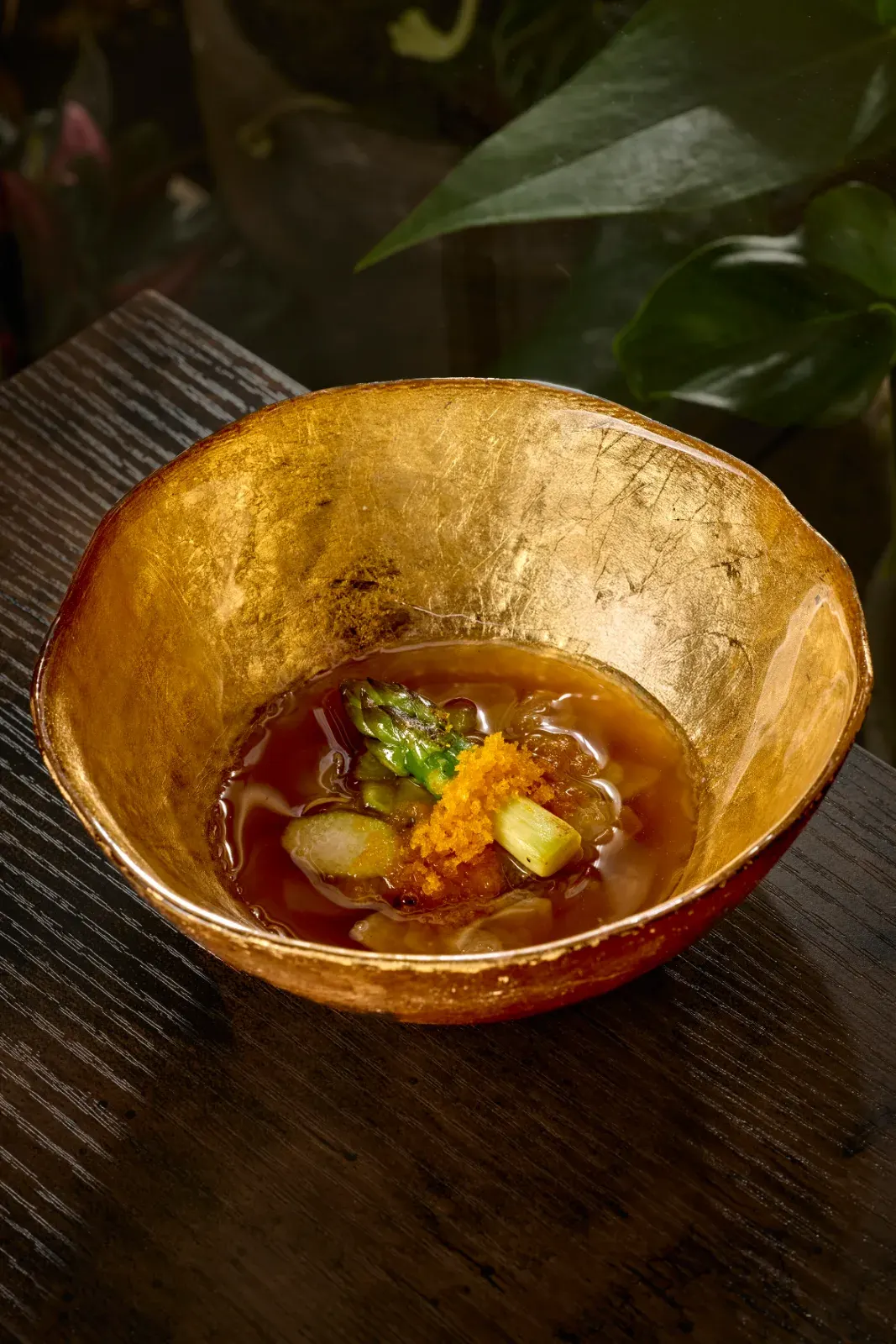 Green asparagus with broth and roe served in a golden bowl