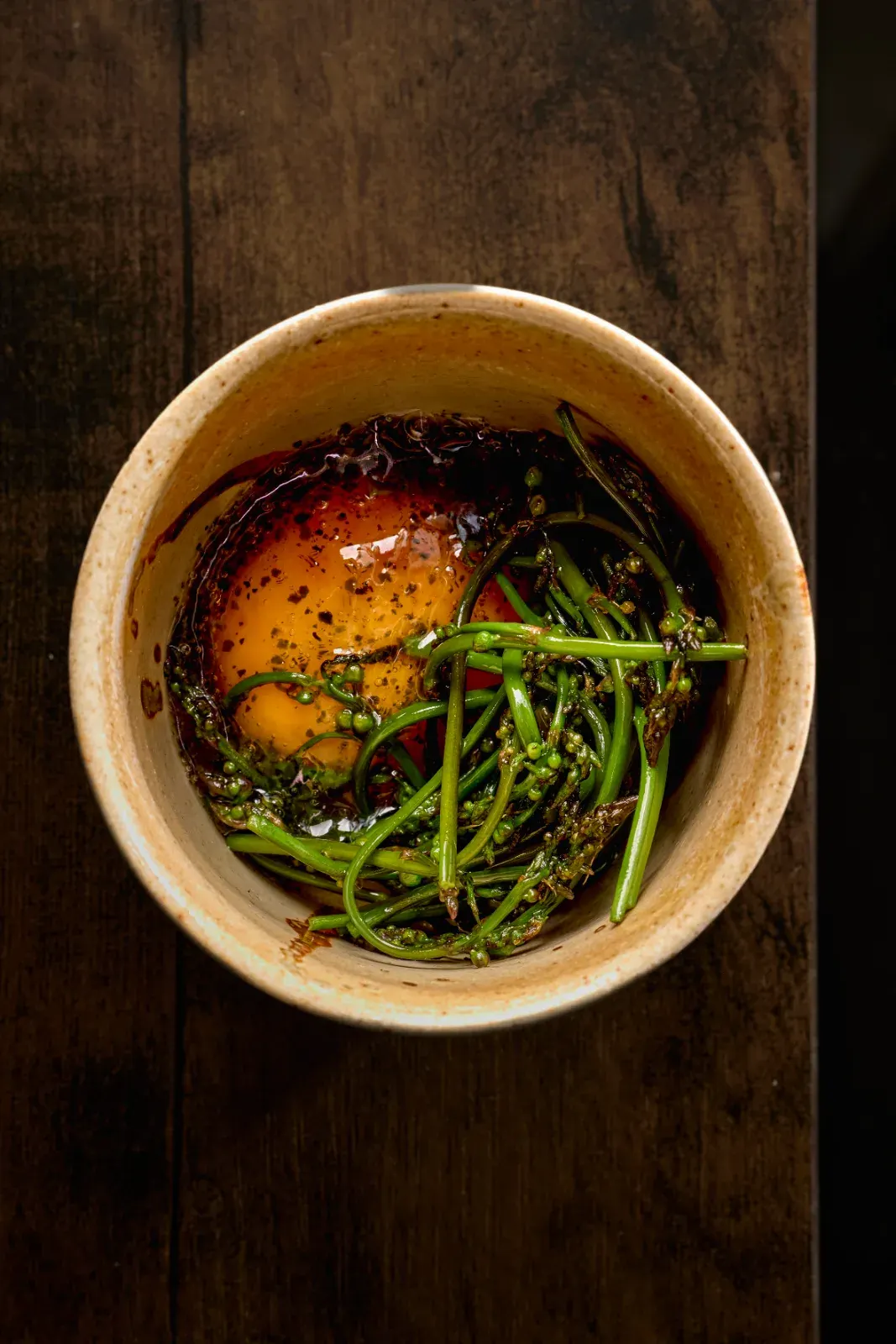Wild asparagus with egg yolk and wakame in an earthenware bowl, one of the tasting menu courses
