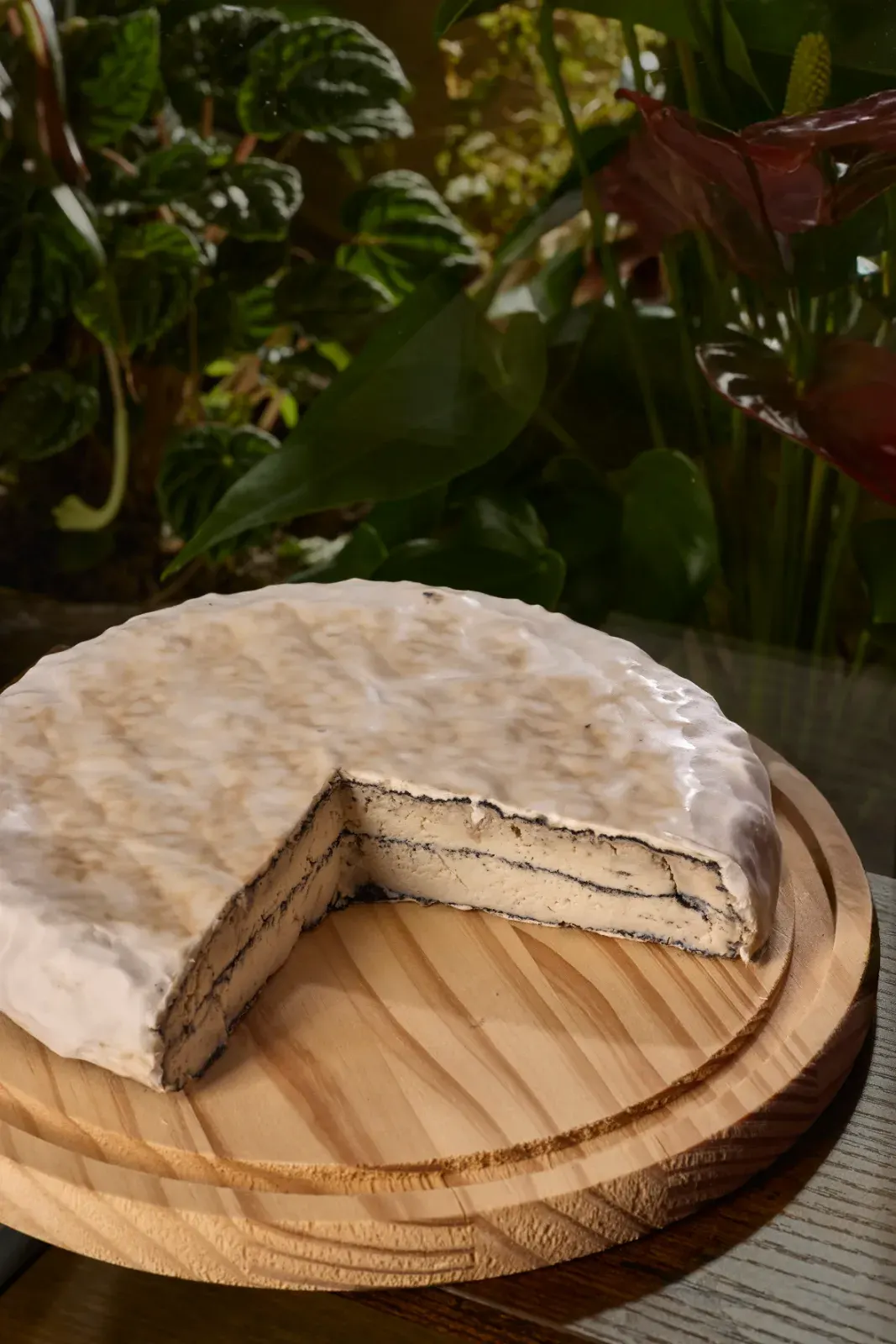 The house cheesecake, whole and with the first slice cut, on a wooden board